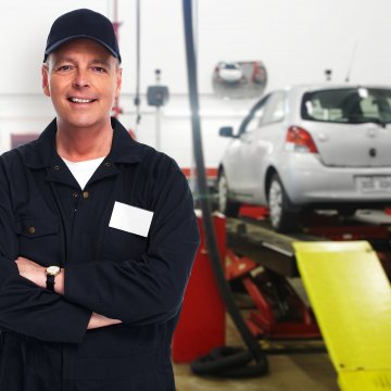 best extended car warranty services providers happy mechanic in uniform smiling towed car on platform in the background 
